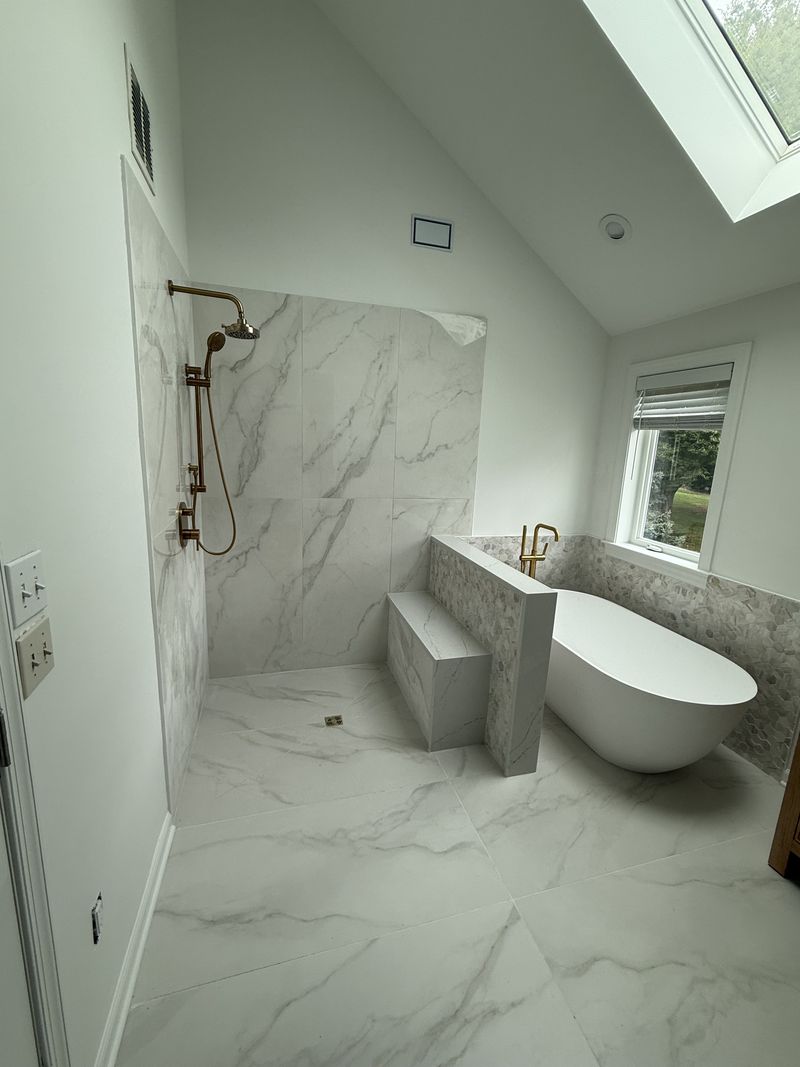 Primary bathroom renovation in Chester County PA with curbless marble-look shower, freestanding tub and skylight